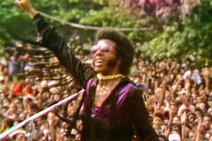 Sly Stone, a Black male musician in violet and black, plays to a huge crowd in Questlove’s ‘Summer of Soul’ (Director: Questlove; Producer: David Dinerstein, Robert Fyvolent, Joseph Patel) Courtesy of Cinetic Media.