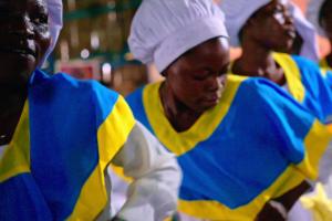 African women chefs in white hats and blue and yellow uniforms.