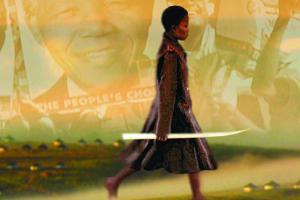 A woman walks with a photo of Nelson Mandela projected onto the background.
