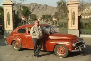 A man stands in front of a red car, from 'Metal and Melancholy', an alternately amusing and touching account of the struggle of impoverished cab drivers in Peru.