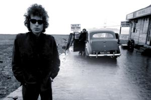 Bob Dylan is standing next to a strip mall