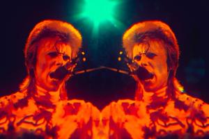 A red overlay on a mirrored image of David Bowie singing into a mic, from ‘Moonage Daydream.’ Photo courtesy of NEON.  