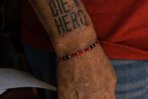 A picutre of a person's arm with 'Die a Hero' tattooed on it.