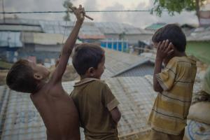 Three young boys living in a refugee camp on a rooftop playing