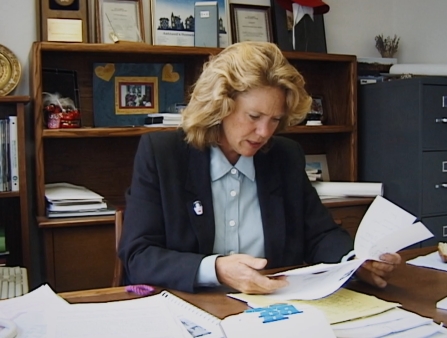 On tape, a woman sits in an office.