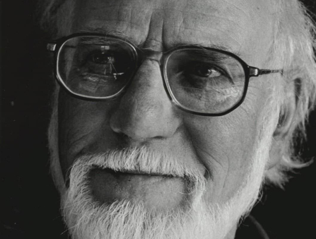A man with a white beard and glasses in close up. 