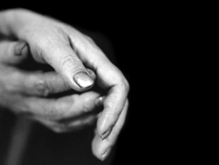 Black and white still of two hands resting against each other.