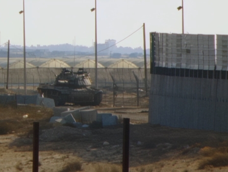 A tank viewed from behind two layers of fences.