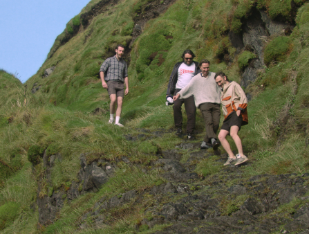Four young people walk down a very steep hill.