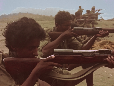 A row of young people with rifles lined up to shoot.