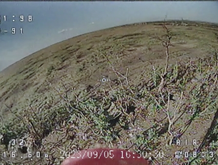 Grainy shot of barren field from the point of view of a drone up above