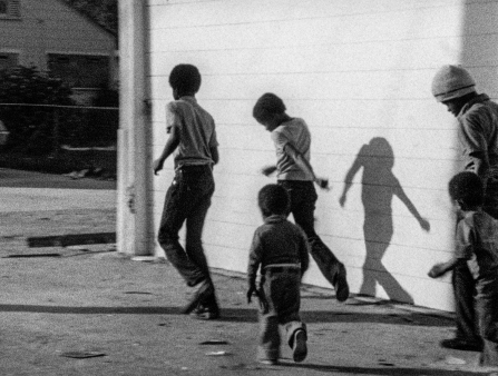 A small group of children run across the street.