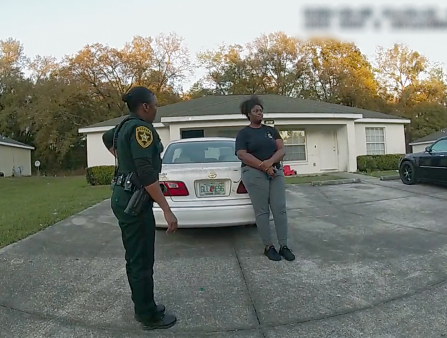 Bodycam still of a Black policewoman and a Black woman in a black t-shirt and grey pants on a driveway.