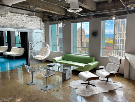 A stylish office with a green couch, clear chairs, bright windows overlooking Koreatown in Los Angeles