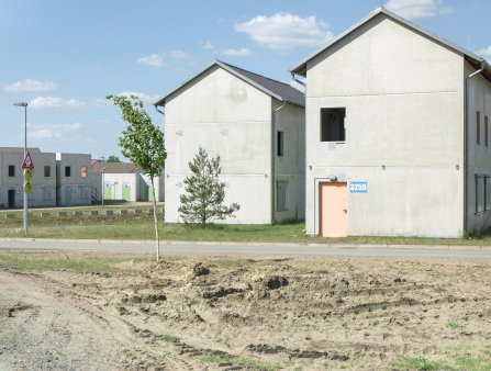 A row of concrete houses sits in the middle of a field on a clear day