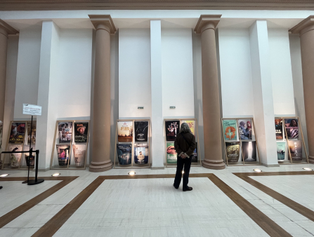 A man stands in front of a row of movie posters.