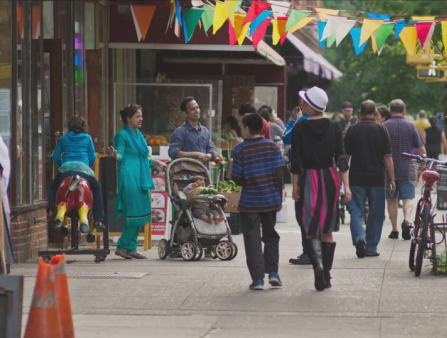 A colorful street scene with colorful flags adorning a New York City sidewalk