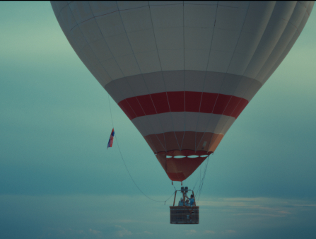 Shot of a hot air balloon on a mostly cloudless sky carrying a few older men
