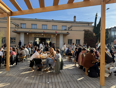 In front of the "Grand Salle," dozens of festivalgoers enjoy the picnic tables in the sun.