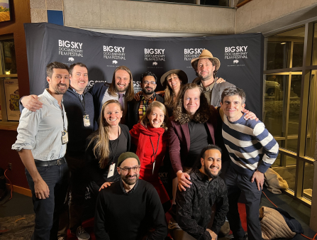 Eight men and four women form three rows, smiling together in front of a background which reads "BIG SKY DOCUMENTARY FILM FESTIVAL"