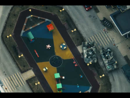 An aerial view of two tanks driving over a road bordering a colorful playground