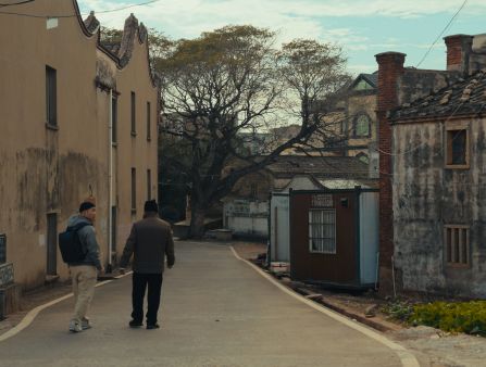 Two grown men in winter clothing can be seen walking down a street on a bright Winter's day