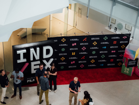 Bird's eye view of a step and repeat for the IND/EX conference with scattered number of attendees milling about
