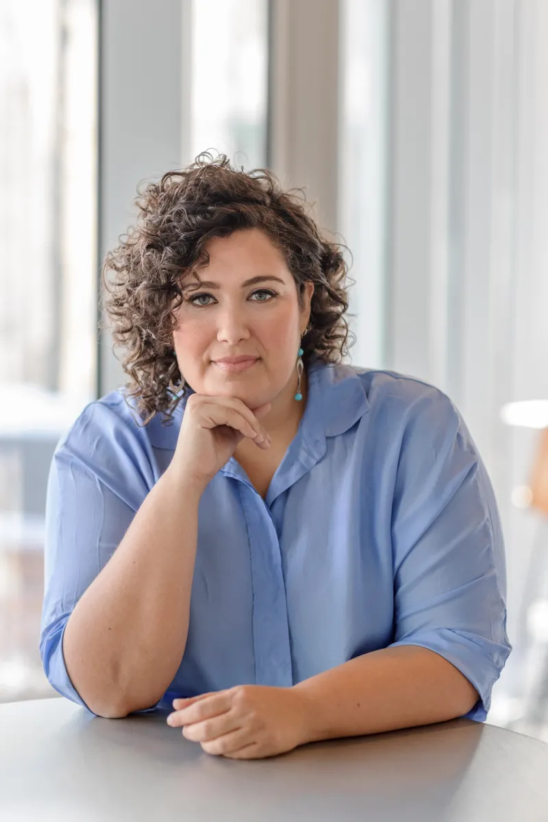 Medium shot of a adult Woman, curly hair, light skin wearing a Blue shirt.