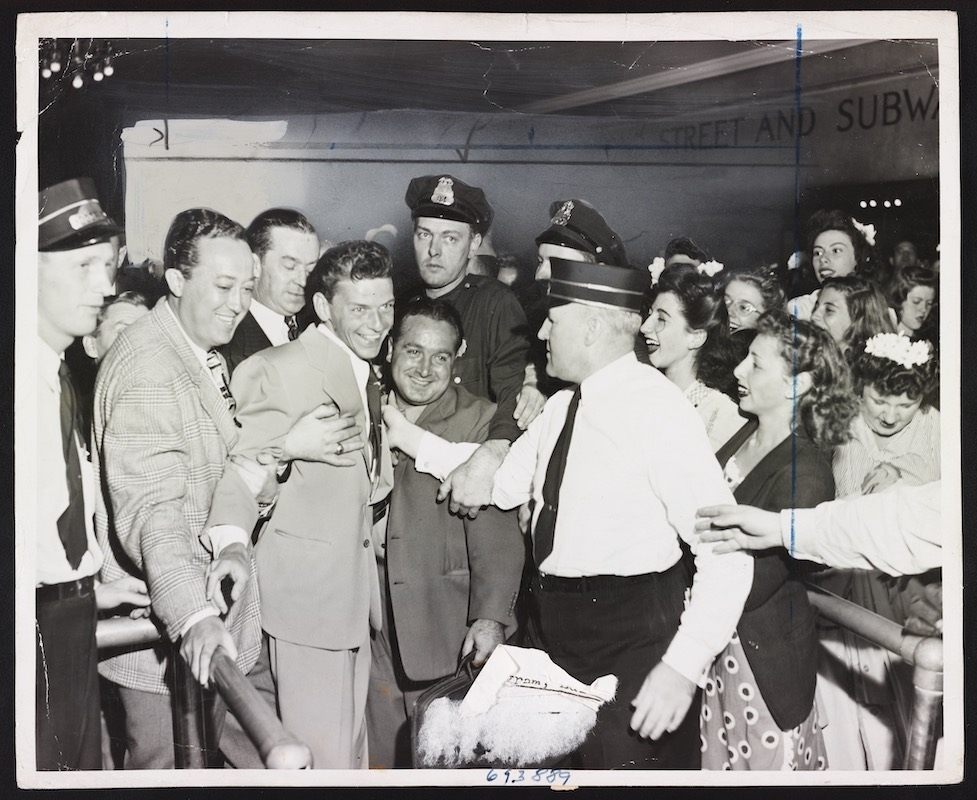 A 1943 NYWTS photo of Frank Sinatra mobbed by fans, found in the Library of Congress. The photo's cutline reads: "It took all these Pasadena, Calif., policemen, if you can believe the story, to rescue singer Frank Sinatra from the hordes of fans that beseiged him when he got off his train at Pasadena. Looks like that old black magic is really taking hold in California."