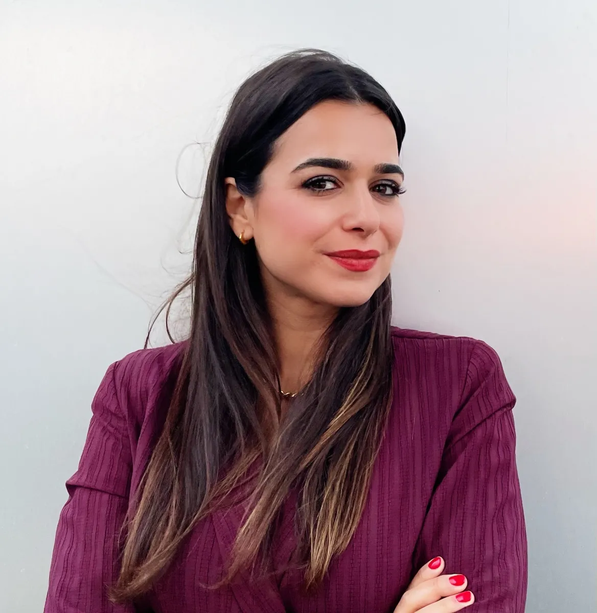 Headshot of an adult woman, long hair, wearing an aubergine colour jacket.