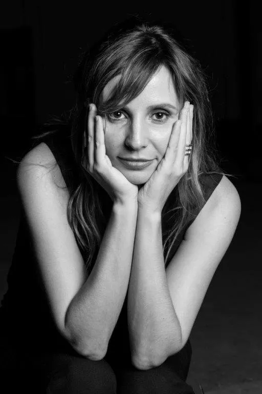 black and white headshot of Petra Costa with the palms of her hands against her cheeks