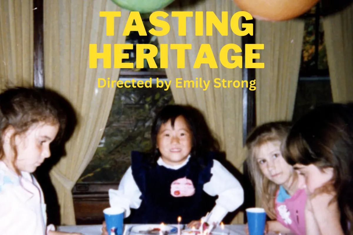 All yellow uppercase film title, "Tasting Heritage" is in the center with the director's name, Emily Strong, below. The text overlaps a birthday photo of a young, approximately six year old Korean-American girl, named Emily Flynn, in front of a platter of cupcakes with lit birthday candles in them. There is one brunette girl on her right side, and one blonde and one brunette girl on her left side, all around the same age.