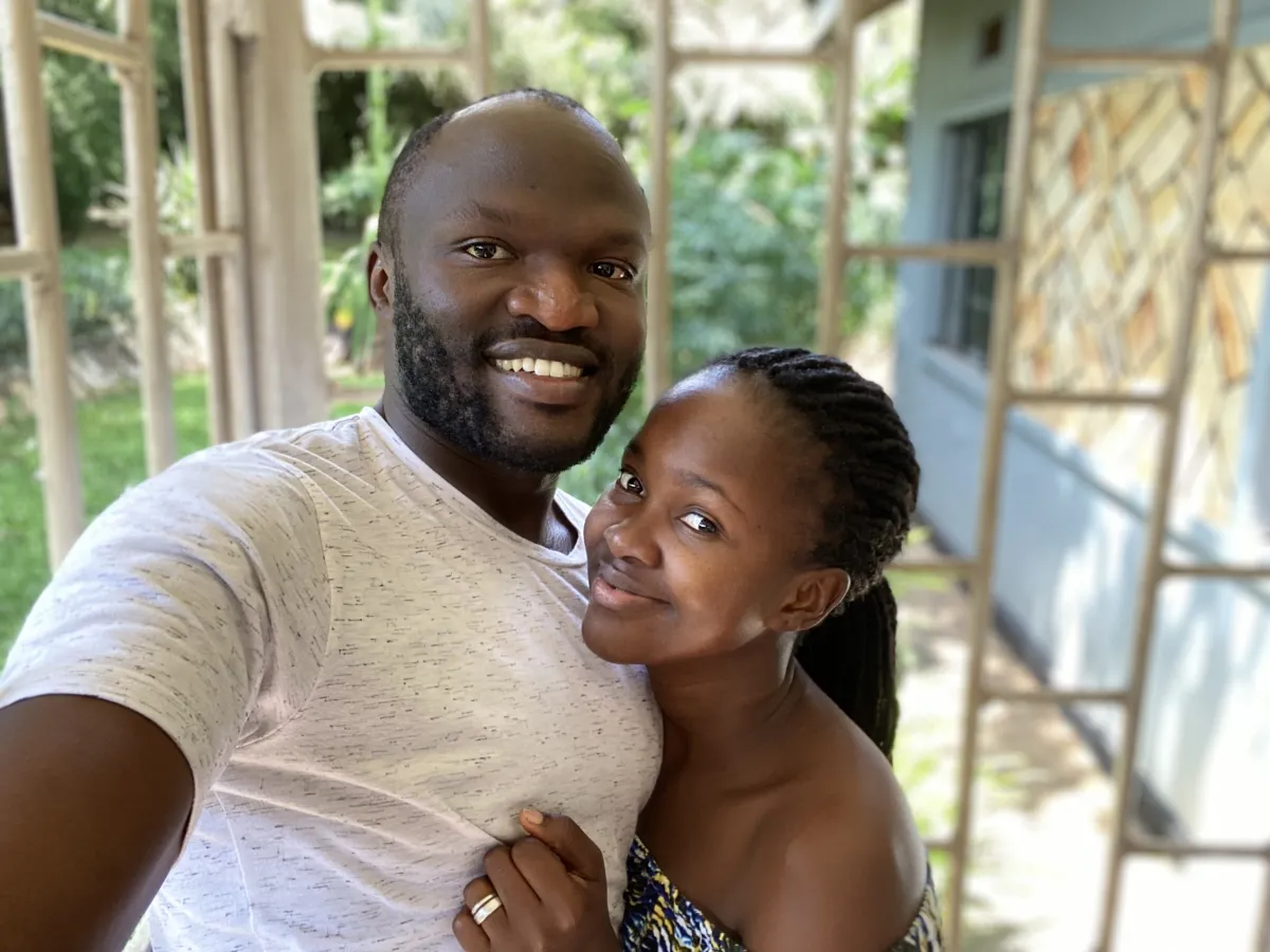 Moses Bwayo and his wife Nulu Bwayo posing together in front of a house and garden