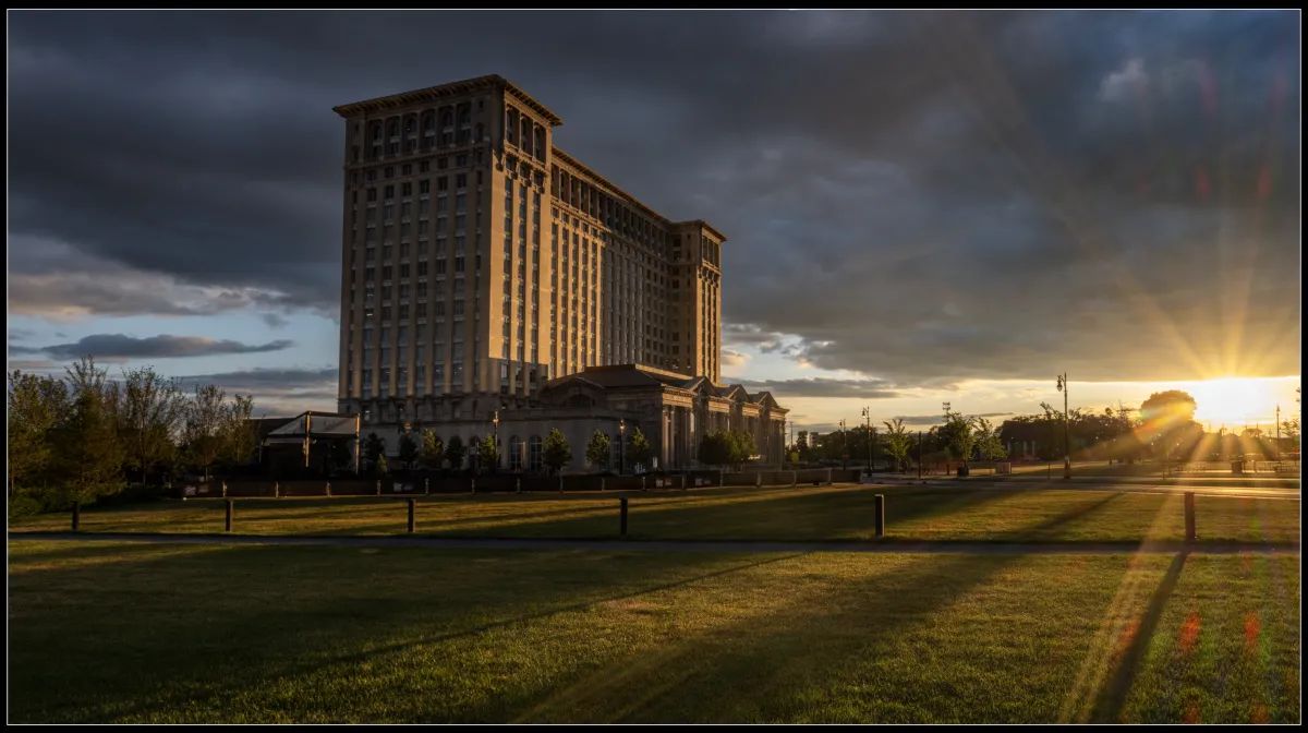 A park with a large building in the background at sunset