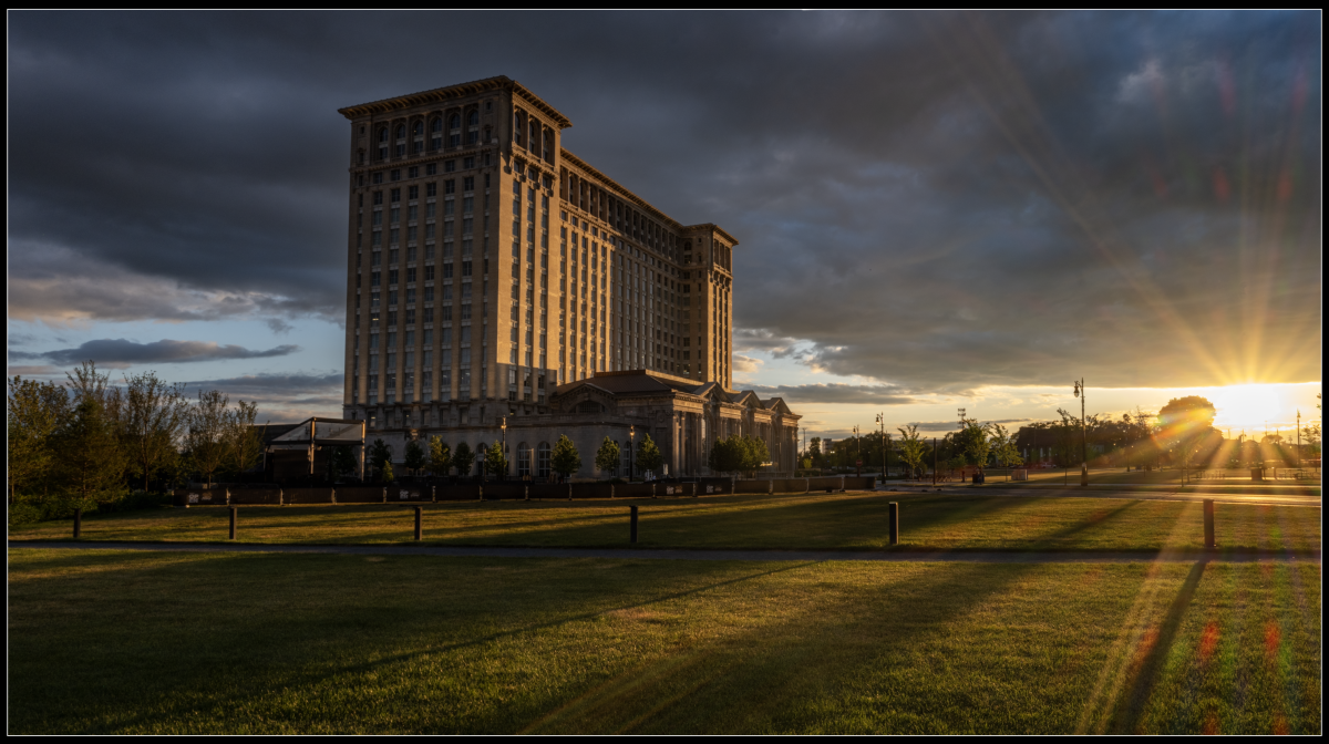 A park with a large building in the background at sunset
