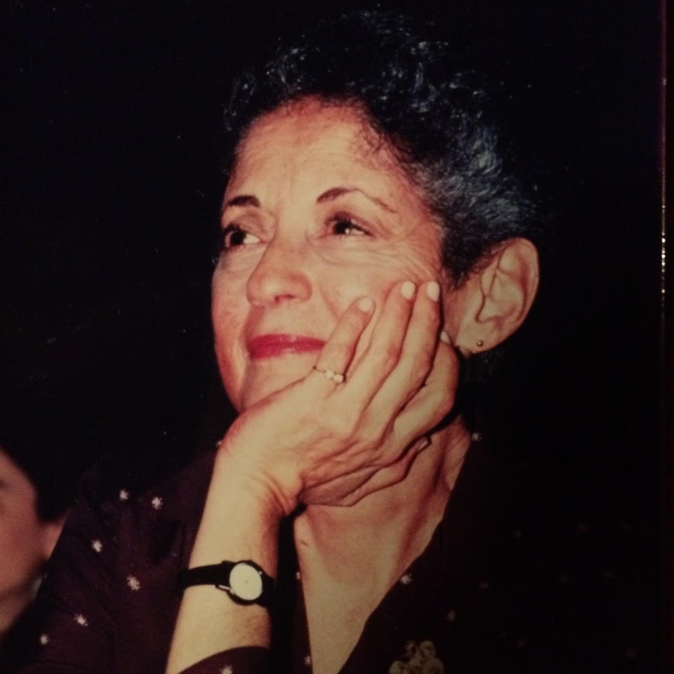 Image of Arlene Carmen, a white woman in her 40's with curly dark hair.  She is smiling and resting her face in hand; she is wearing a gold ring and a wristwatch.