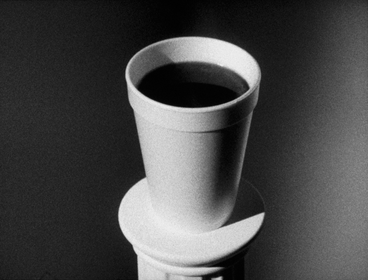 A black and white image of a cup holding a dark liquid.