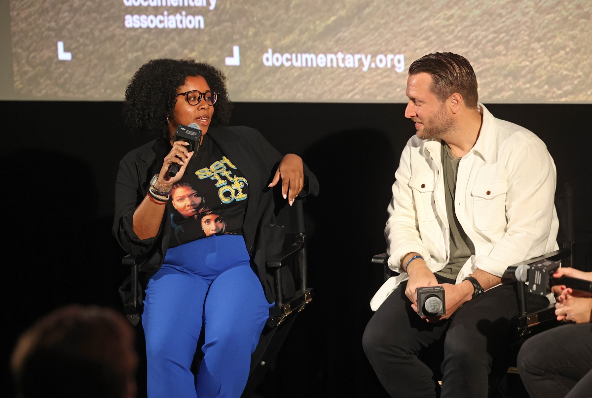 Two filmmakers seated on director's chairs look at each other during a Q&A.