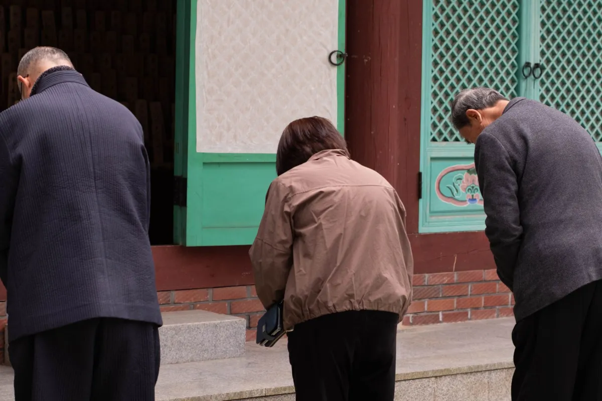 Three individuals wearing jackets bowing with their backs to the camera