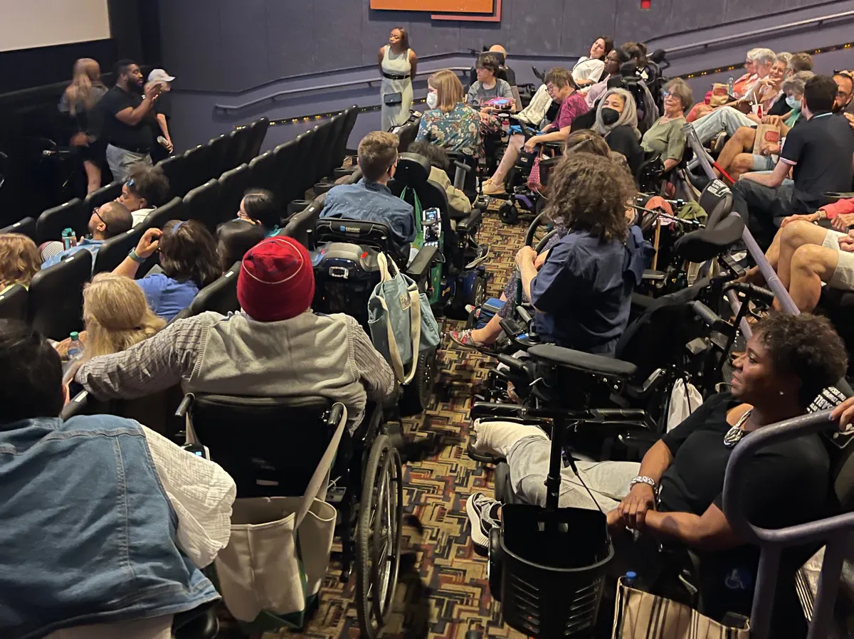 In a movie theater landing, more than 10 people using wheelchairs crowd into all available space.