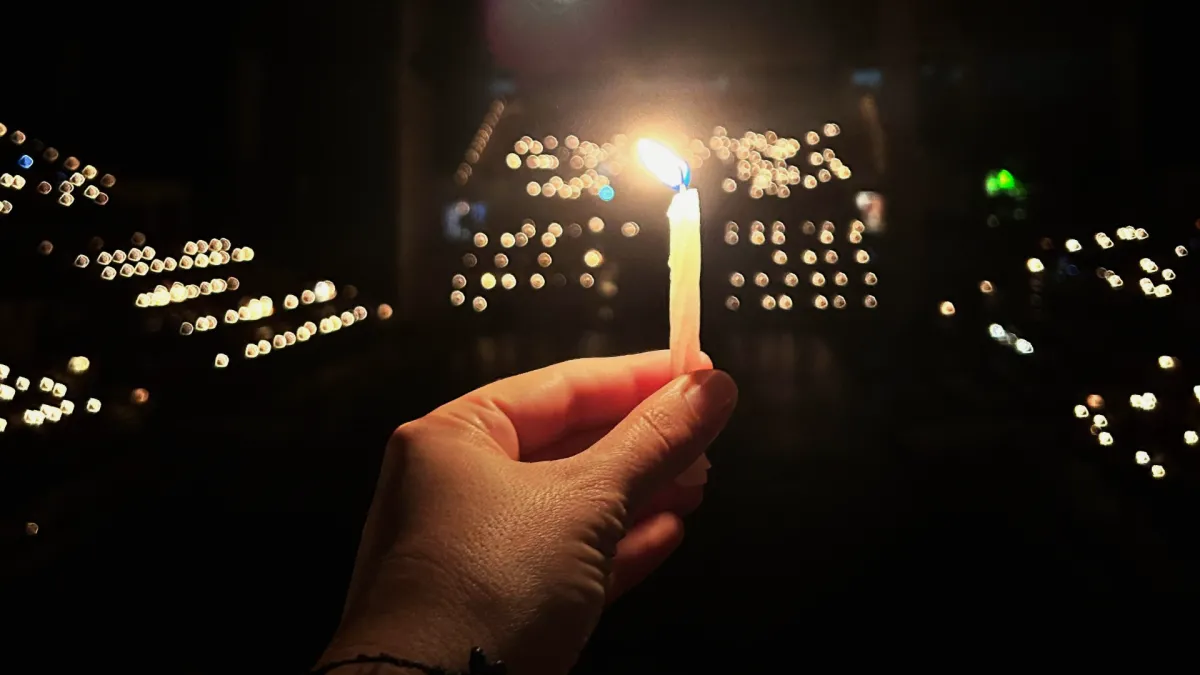 a hand hold a camera in front of far away lights. 