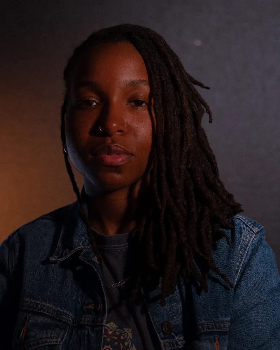 Head shot of black person with moody and multi colored neutral lighting. they glow. 