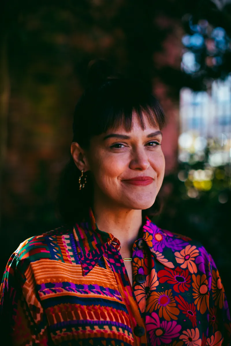 photo of white woman with brown hair and short bangs in a colorful flower button up