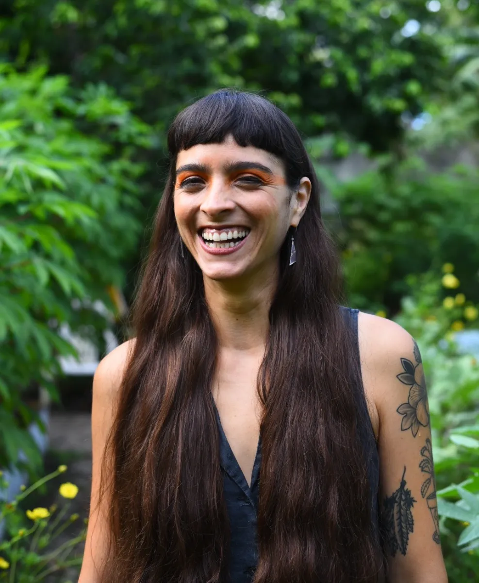 head shot of borwn woman with long brown hair and heavy bangs smiling