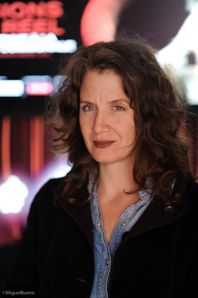 white woman with long brown hair and a blurred background with lights 