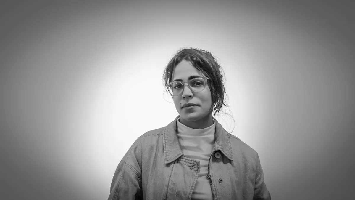 black and white photo of a white woman with glasses and a turtle neck and a jean jackey