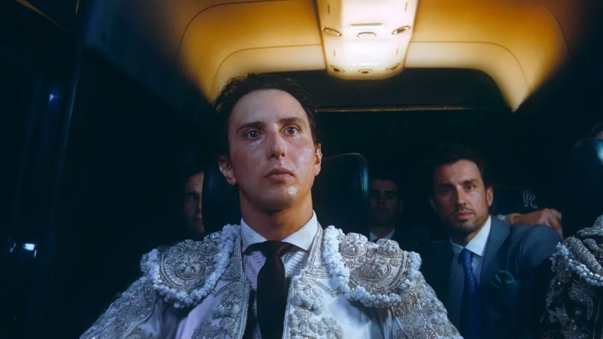 Inside a van, a man in an elaborate bullfighting outfit sits surrounded by his entourage.