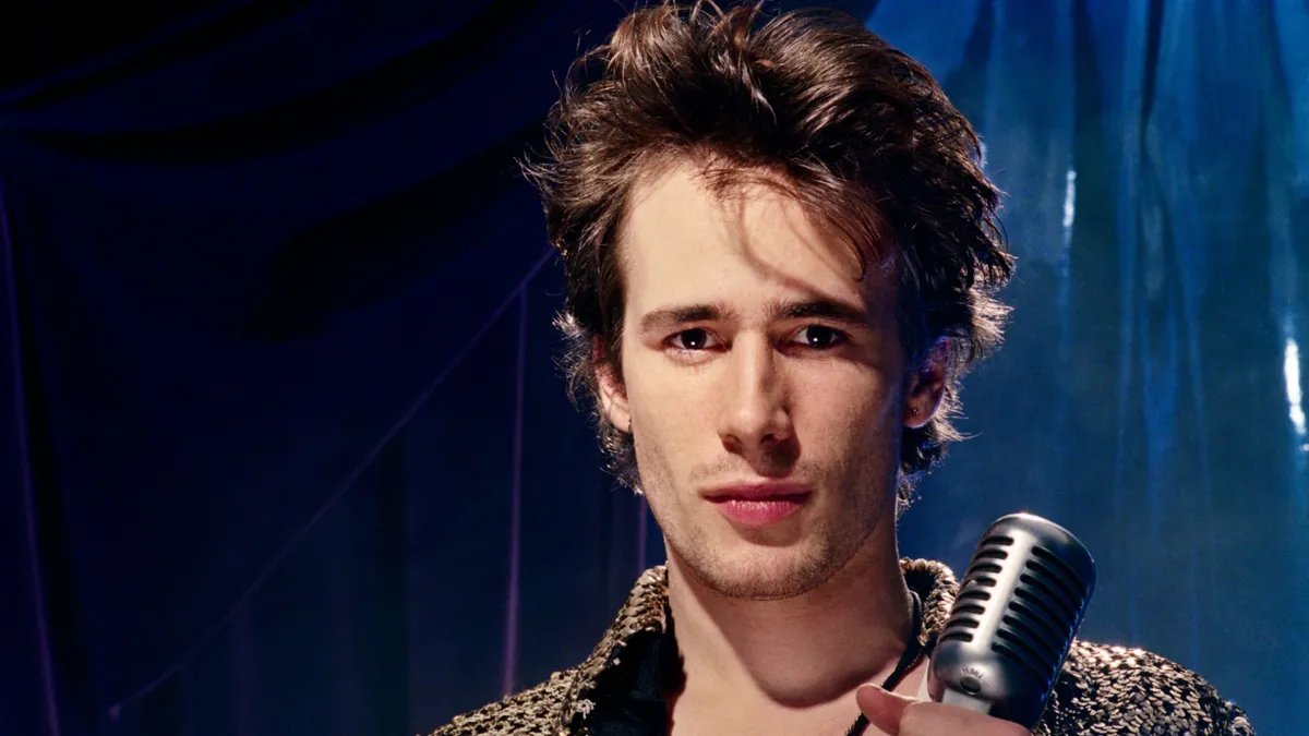 Still image of Jeff Buckley, holding a microphone.