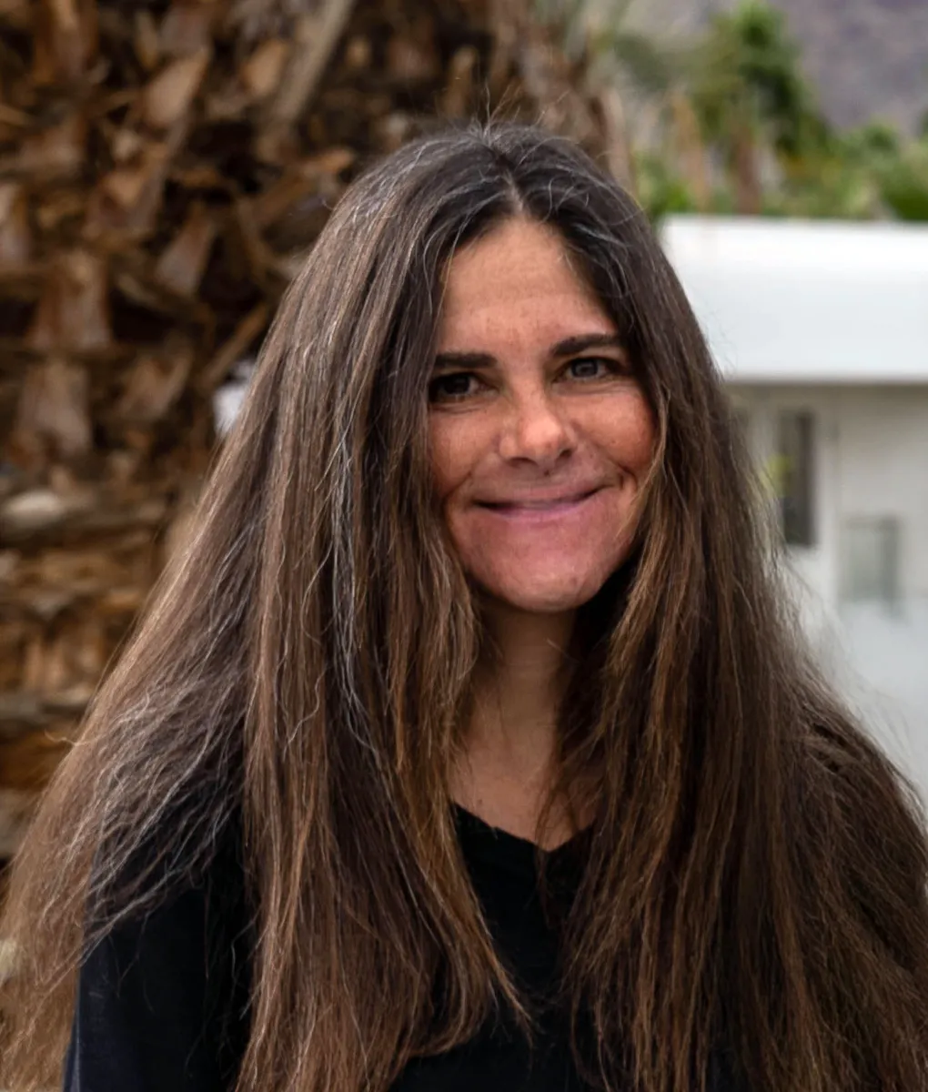 A woman with long brown hair smiles at the camera. 