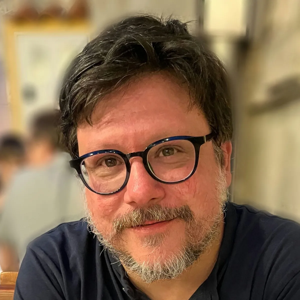 A man with glasses and a beard gazes at the camera. 